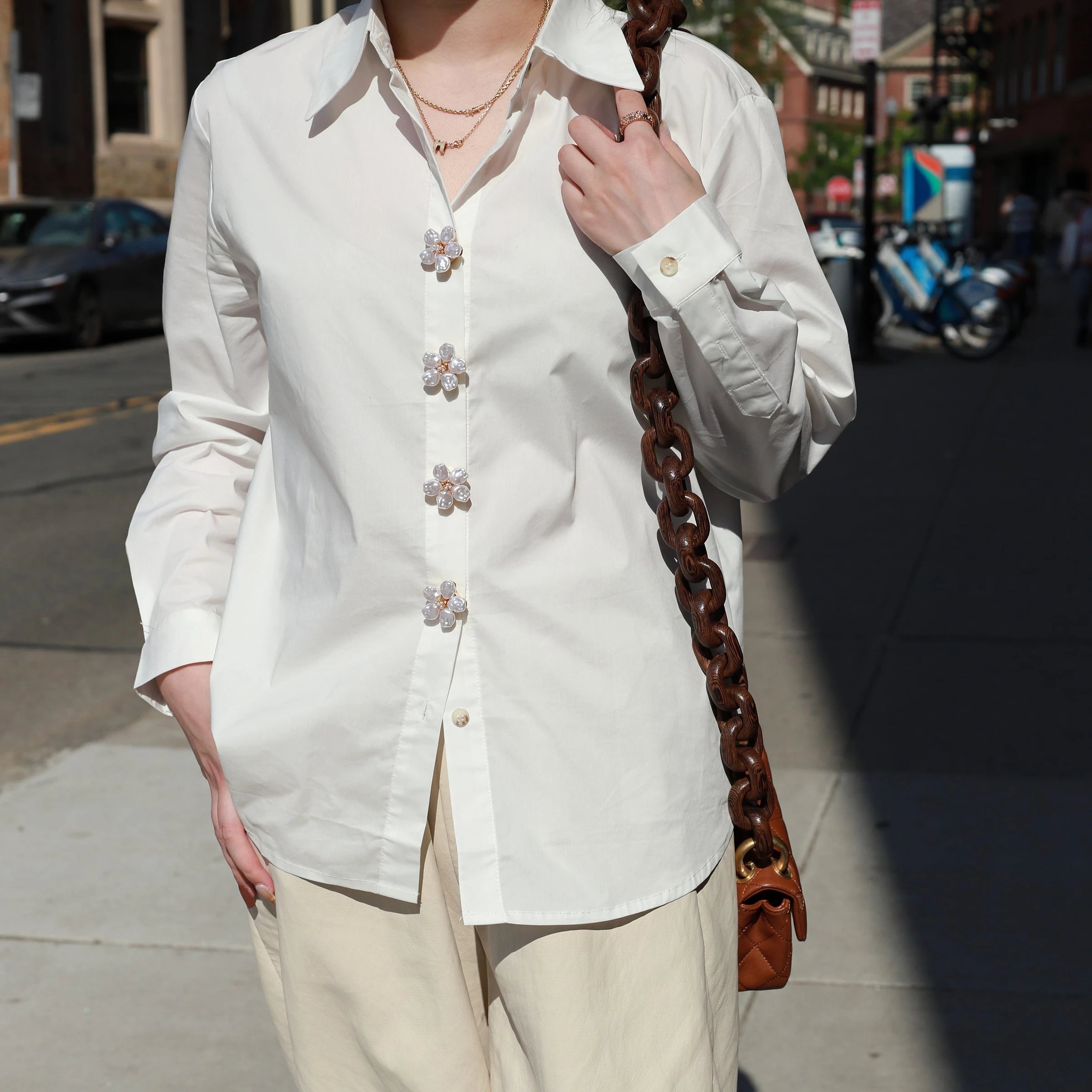 Person wearing a white shirt with Astral Flora pearl Button Covers on Boston street