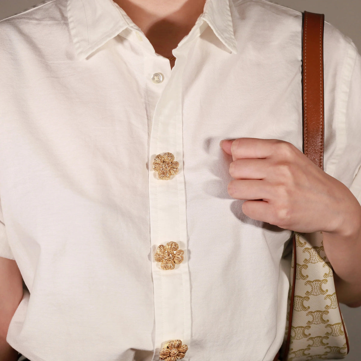Close-up of a person wearing a white button-up shirt and Aurelian Petal Clip on button cover 