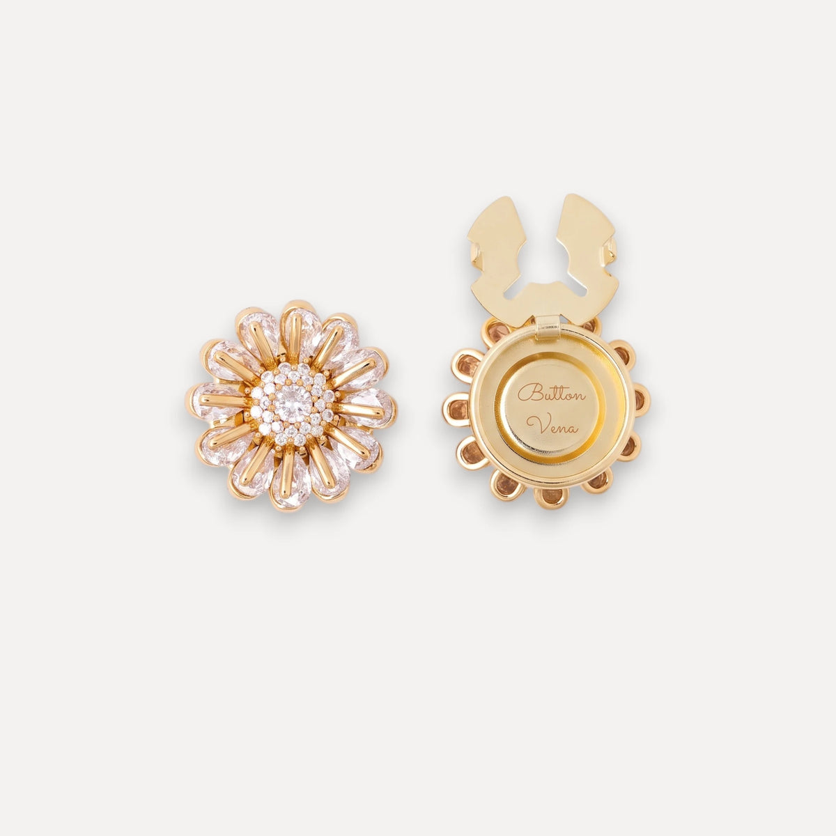 Bellis gold daisy clip-on button cover with hand-set cubic zirconia shown from both the front and back. The front features bellis design surrounding a round cluster of clear stones, while the back shows a circular gold plate engraved with 'Button Vena'.