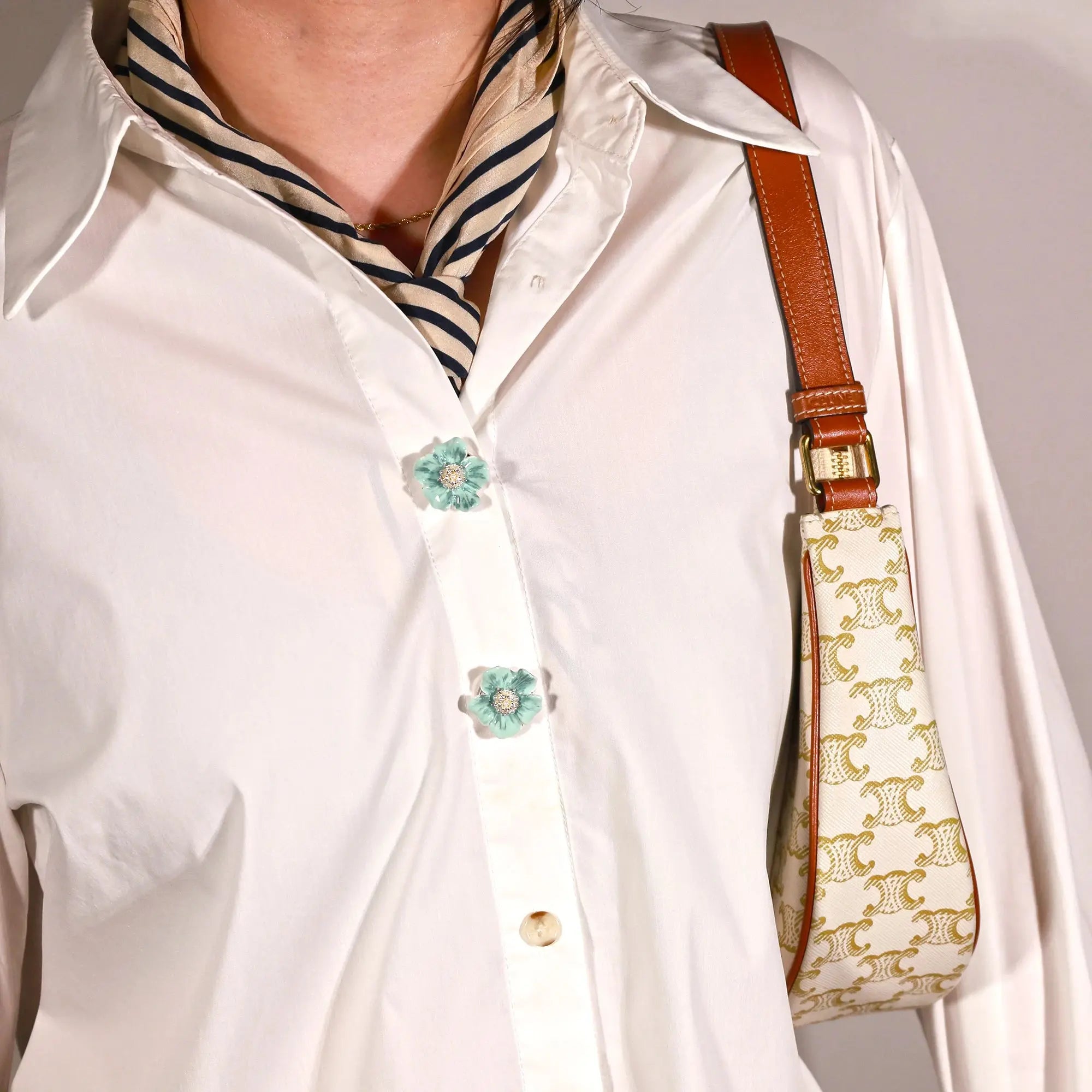 A close up of a person wearing Cerulean Dream flower clip on button cover on a plain white shirt