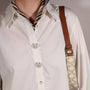A close-up of a person wearing a white button-up shirt with decorative floral button cover, the iris from button vena
