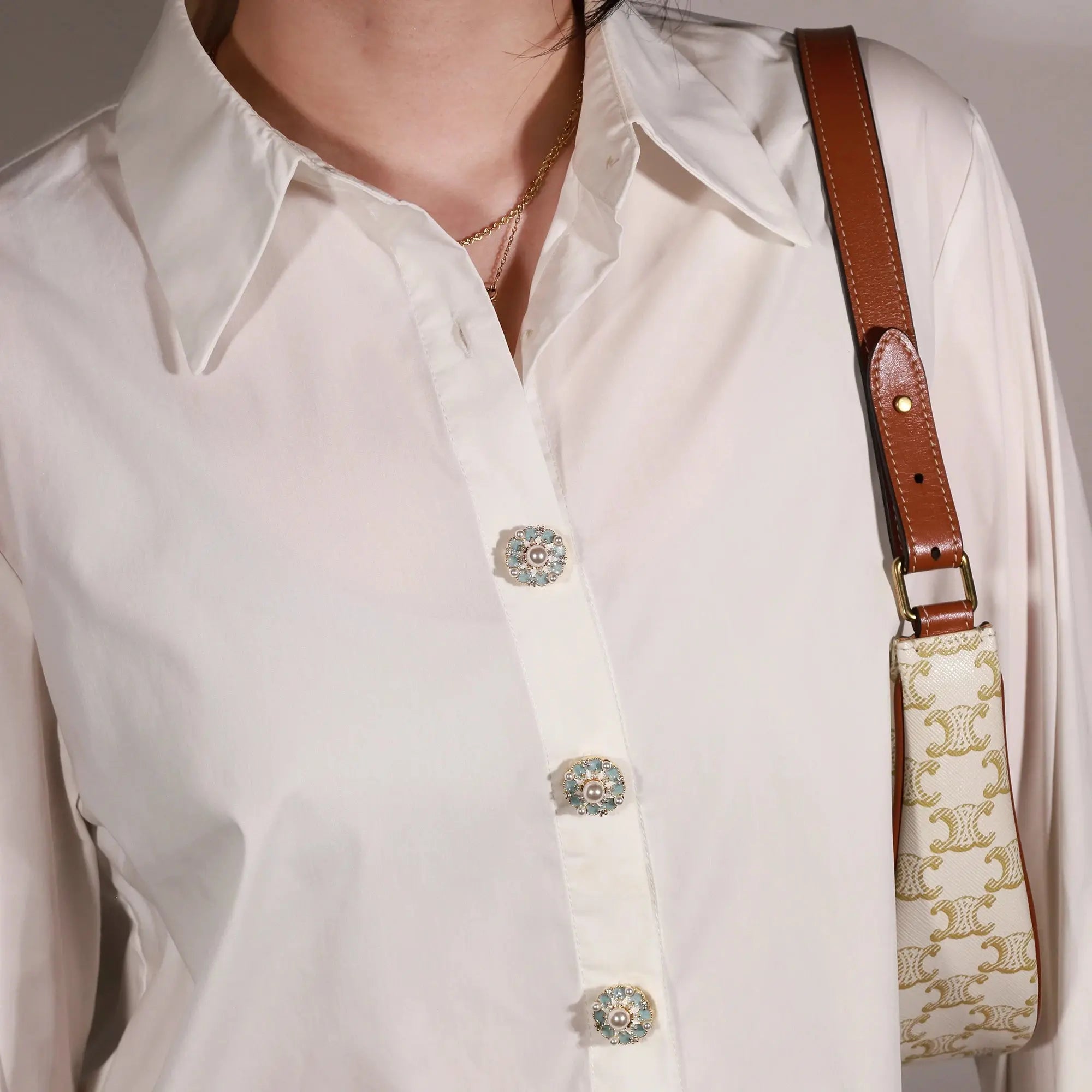 A close-up of a person wearing a white button-up shirt with a macaron d'azure button cover from button vena
